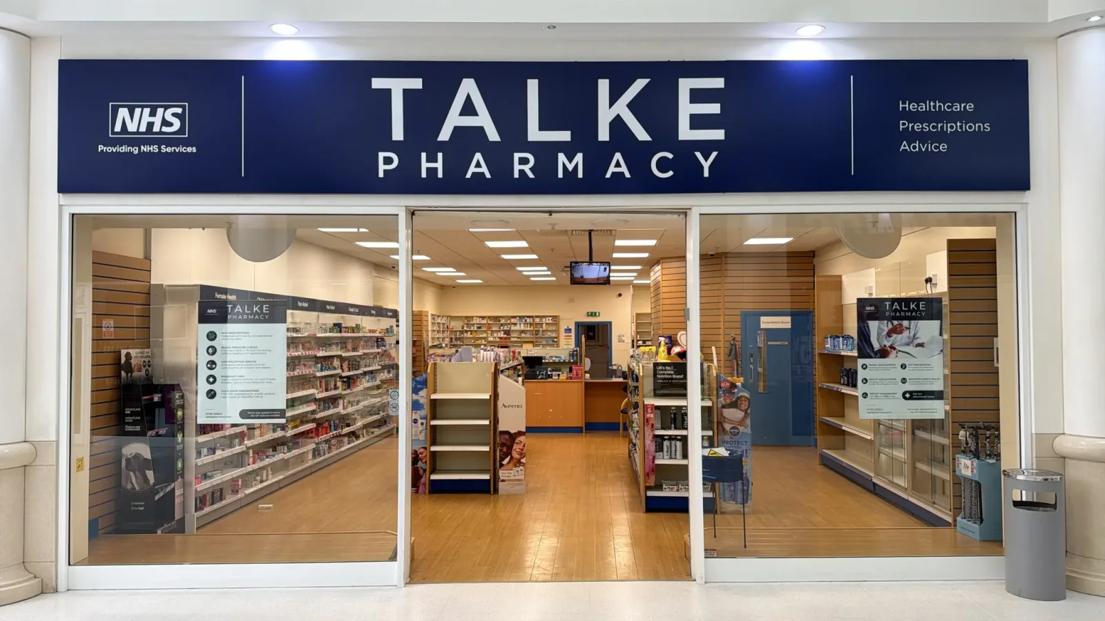 The Talke Pharmacy shopfront inside Freeport Shopmall, with the NHS logo and the pharmacy name above the entrance
